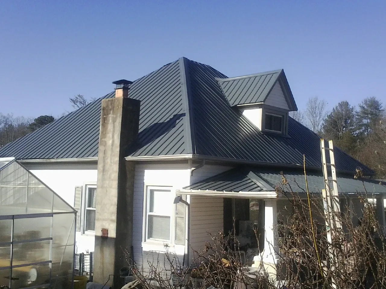 Dark blue standing seam metal roof on a white farmhouse with dormer — Slate & Tile Roof Repair by Roofing Brothers in Cottonwood